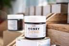 Leafia Skincare honey goat milk face and eye cream jar with white lid on wooden boxes in warm apothecary setting