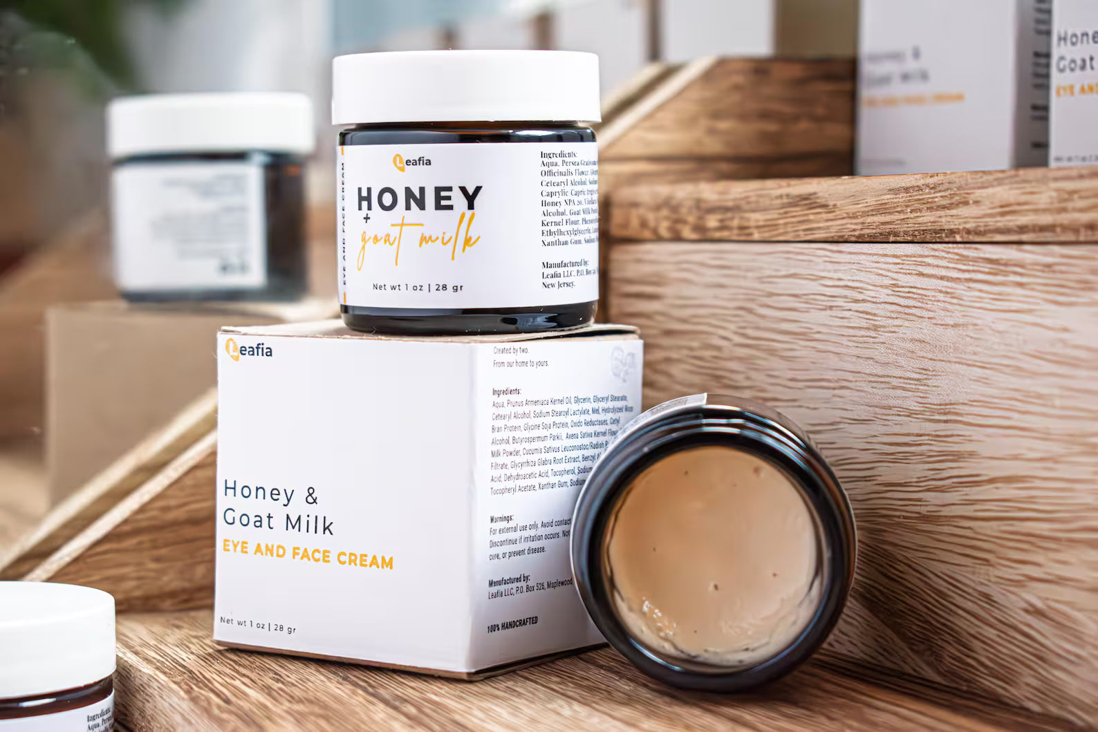 Open jar of Leafia Skincare honey goat milk face and eye cream with smooth texture, styled with matching jars on wood