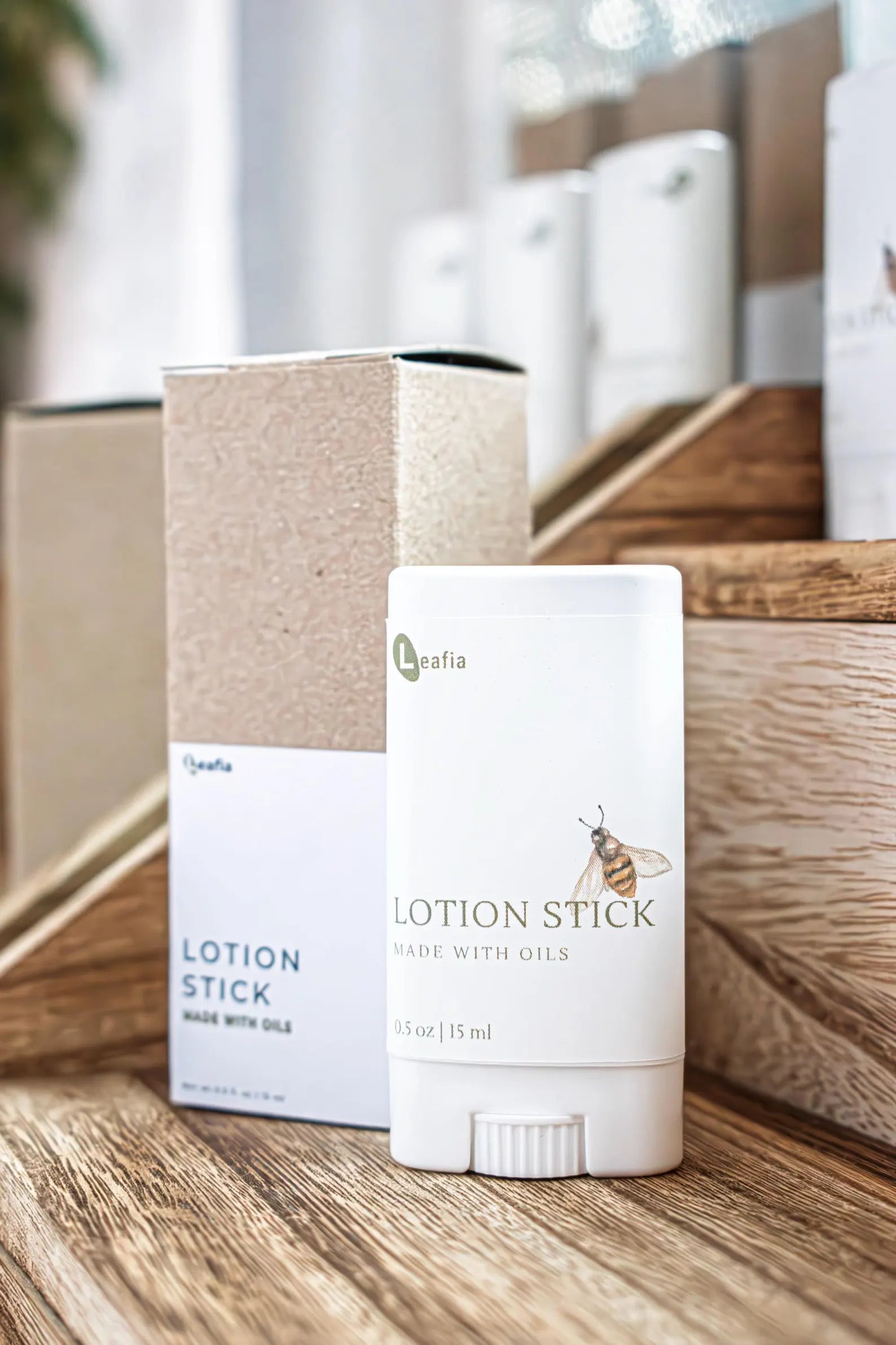 Leafia Skincare lotion sticks made with nourishing oils beside kraft box on wooden surface