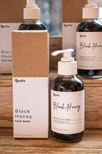 Leafia Skincare Black Honey charcoal cleanser honey gel face wash in dark glass pump bottle on stacked packaging in soft natural light
