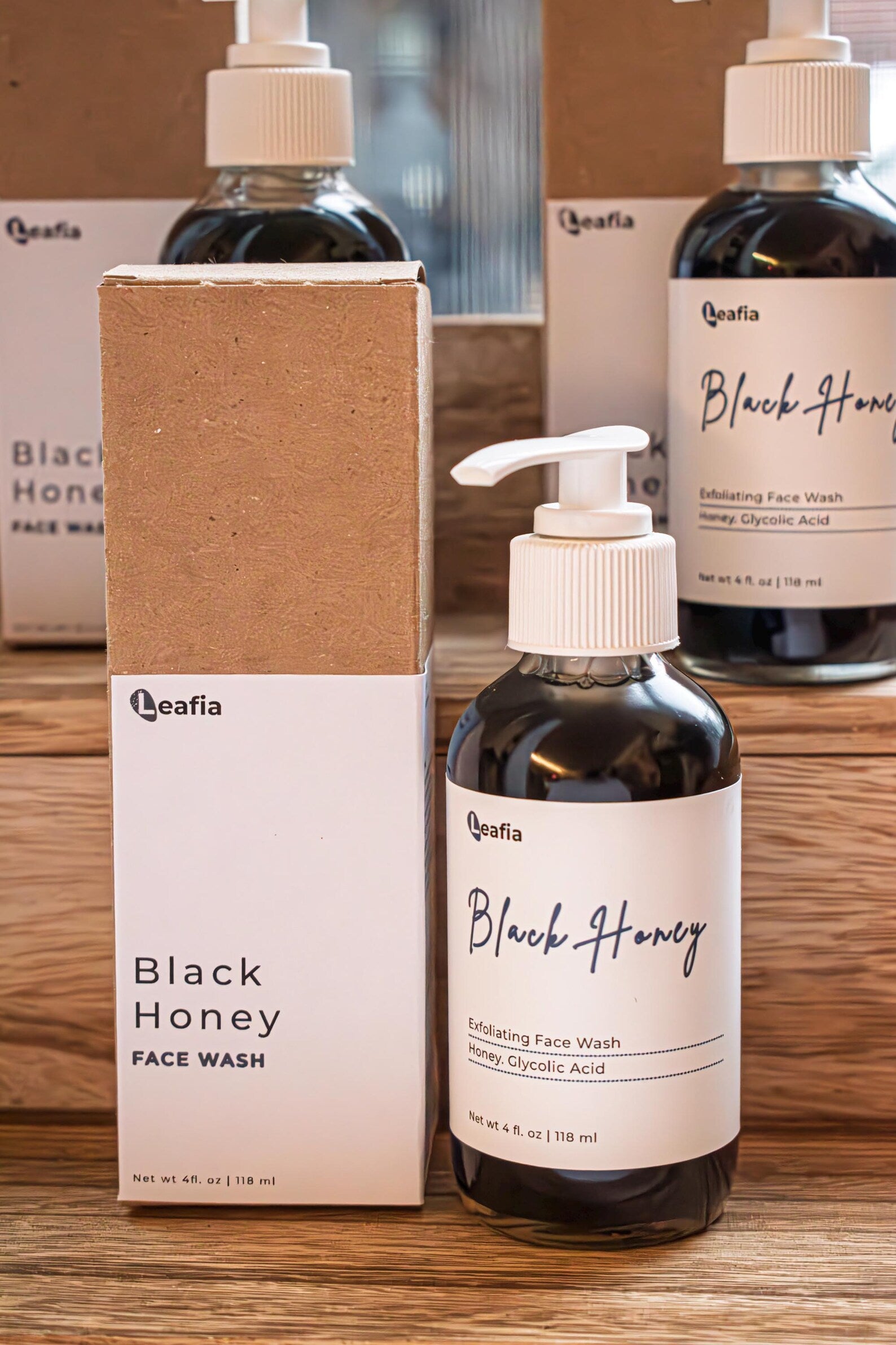 Leafia Skincare Black Honey charcoal cleanser honey gel face wash in dark glass pump bottle on stacked packaging in soft natural light
