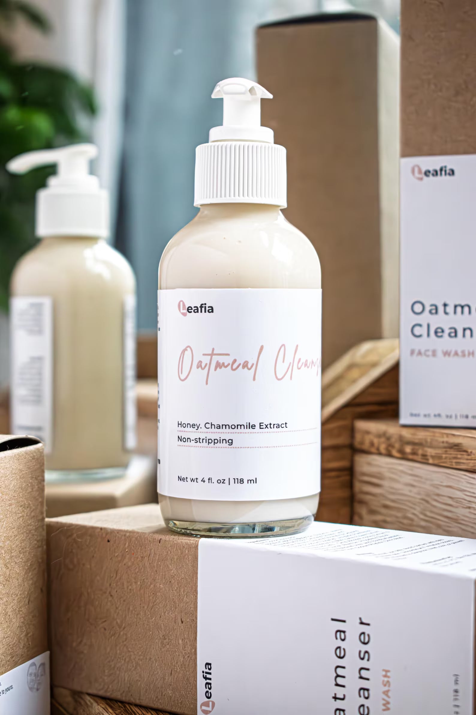 Leafia Skincare Oatmeal Cleanser gentle cream facial cleanser in clear pump bottle beside packaging on wood in soft natural light