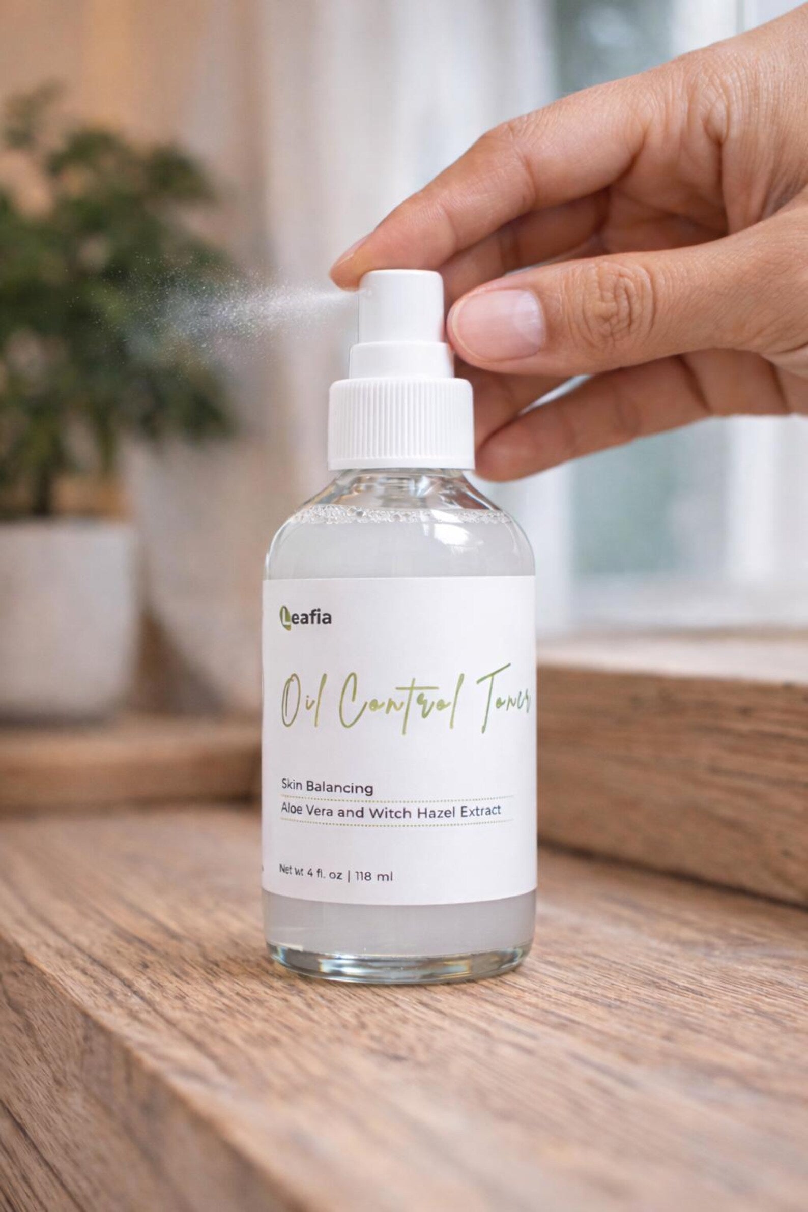 Hand pressing Leafia Skincare oil control toner spray nozzle, releasing fine mist
