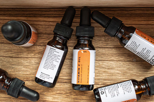 Leafia Skincare Vitamin C facial oil bottles with black droppers on wood, amber glass, white labels, minimal packaging
