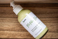 Leafia Skincare Matcha Green Tea facial cleanser bottle on wooden surface, creamy pale green formula visible through clear packaging