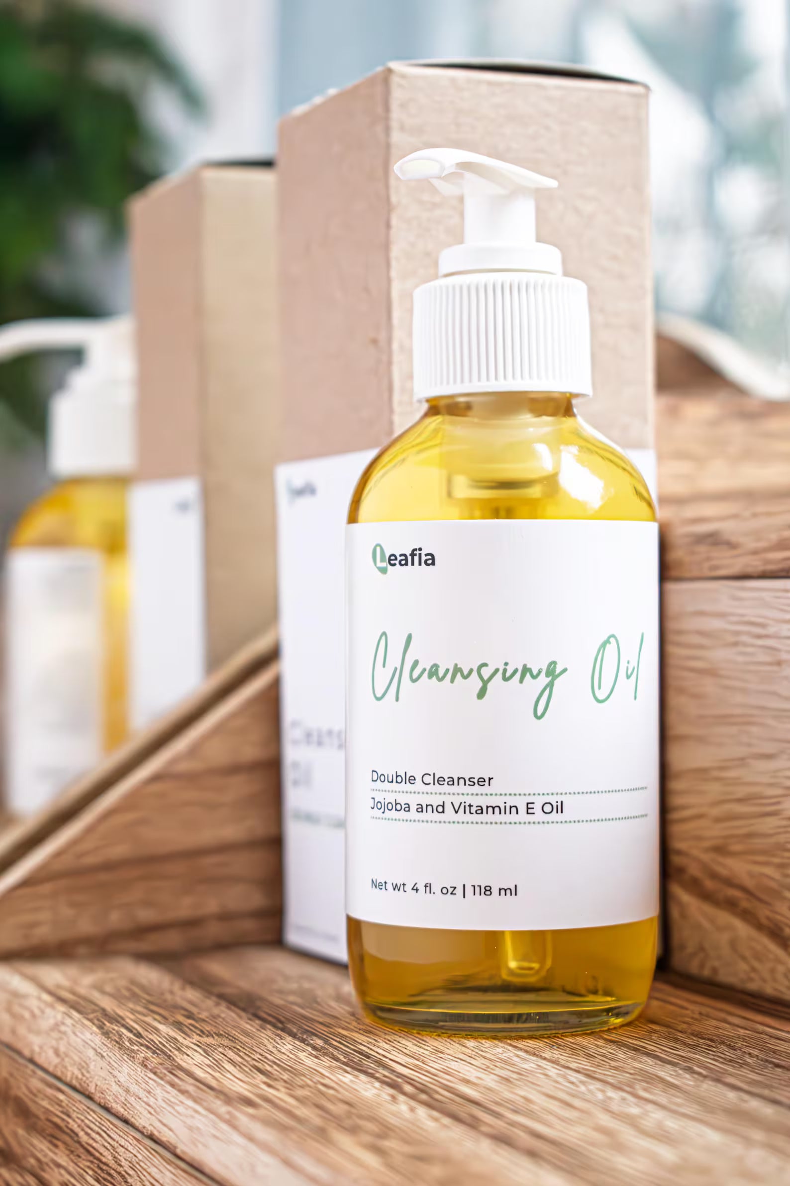Leafia Skincare cleansing oil in clear pump bottle on layered wood with soft daylight and minimal apothecary styling