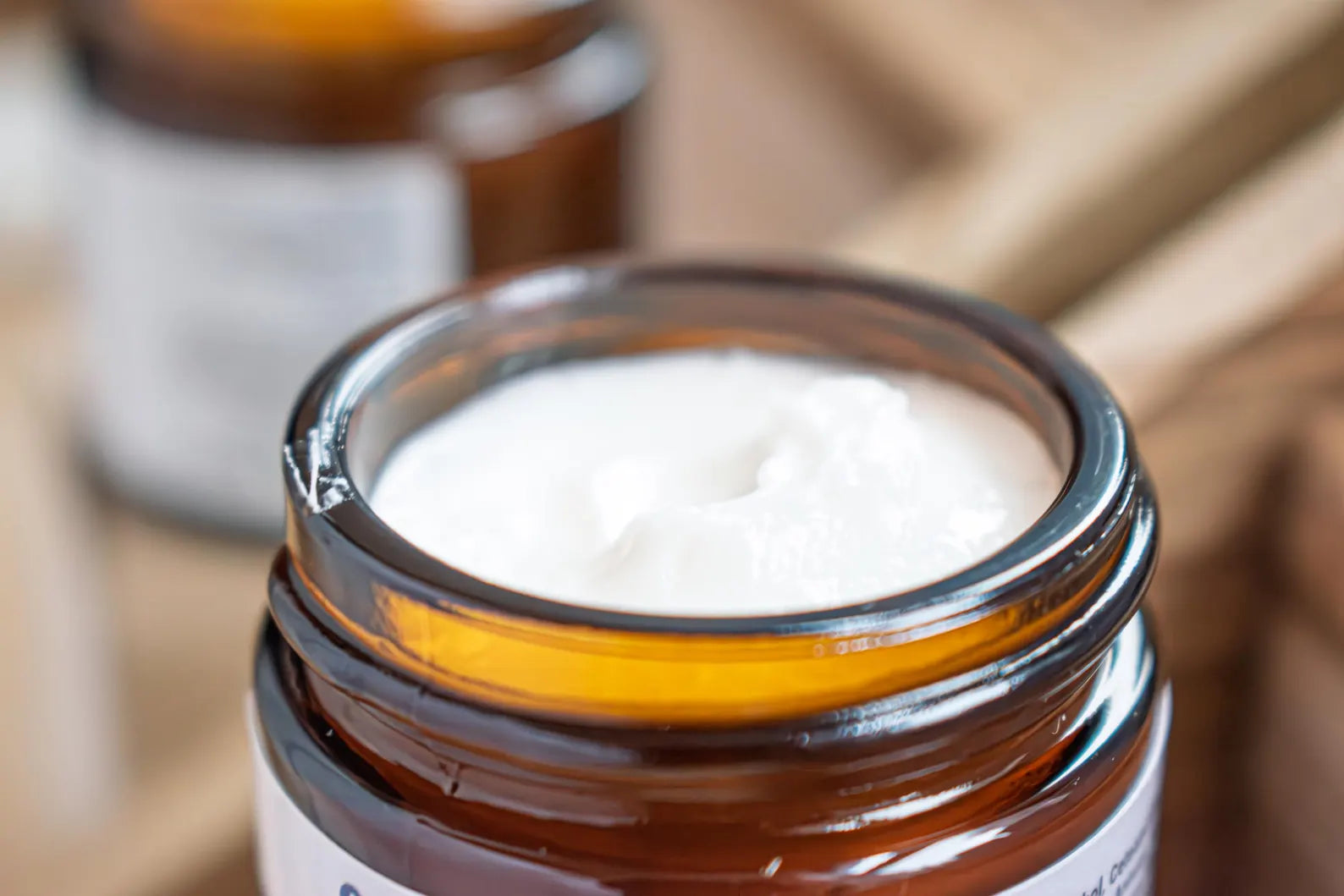 Leafia Skincare retinol and ceramides night moisturizer in open amber jar on natural wood, shown from above