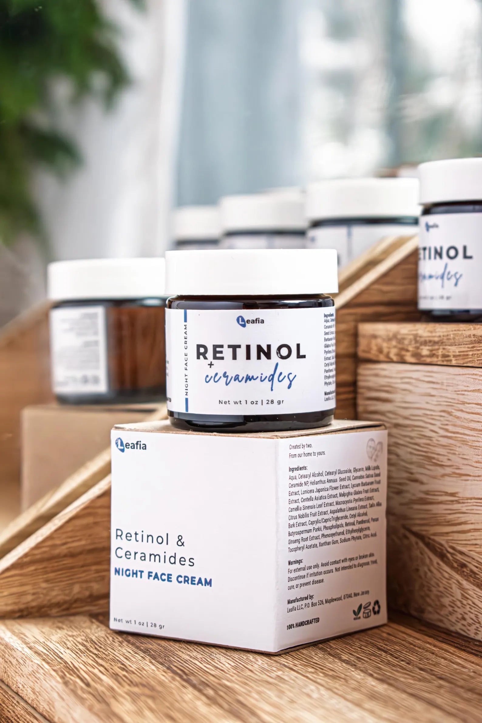 Leafia Skincare retinol and ceramides night moisturizer in amber glass jar with packaging on wood blocks in soft diffused light