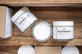 Leafia Skincare Vitamin E apricot oil lotion face and body moisturizer shown above with open jar, closed jar and packaging on natural wood
