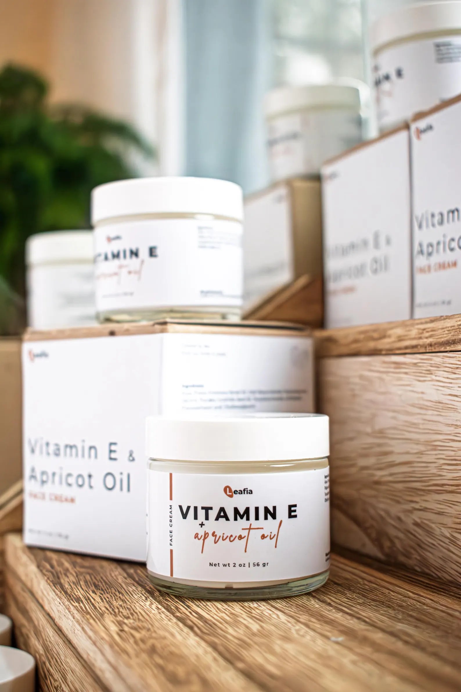 Leafia Skincare Vitamin E apricot oil lotion in white jar with packaging on wood blocks in soft natural light