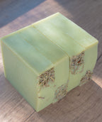 Green soap bar with visible herbs on a wooden surface