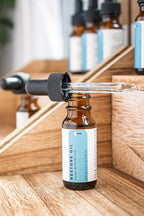 Leafia Skincare Restore Oil facial oil in amber dropper bottles on wood blocks, soft light and minimal apothecary styling
