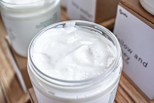Leafia Skincare open jar of tallow body butter showing rich whipped texture in clear glass container with soft natural light