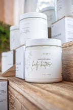 Leafia Skincare body butter container on a wooden surface with blurred background