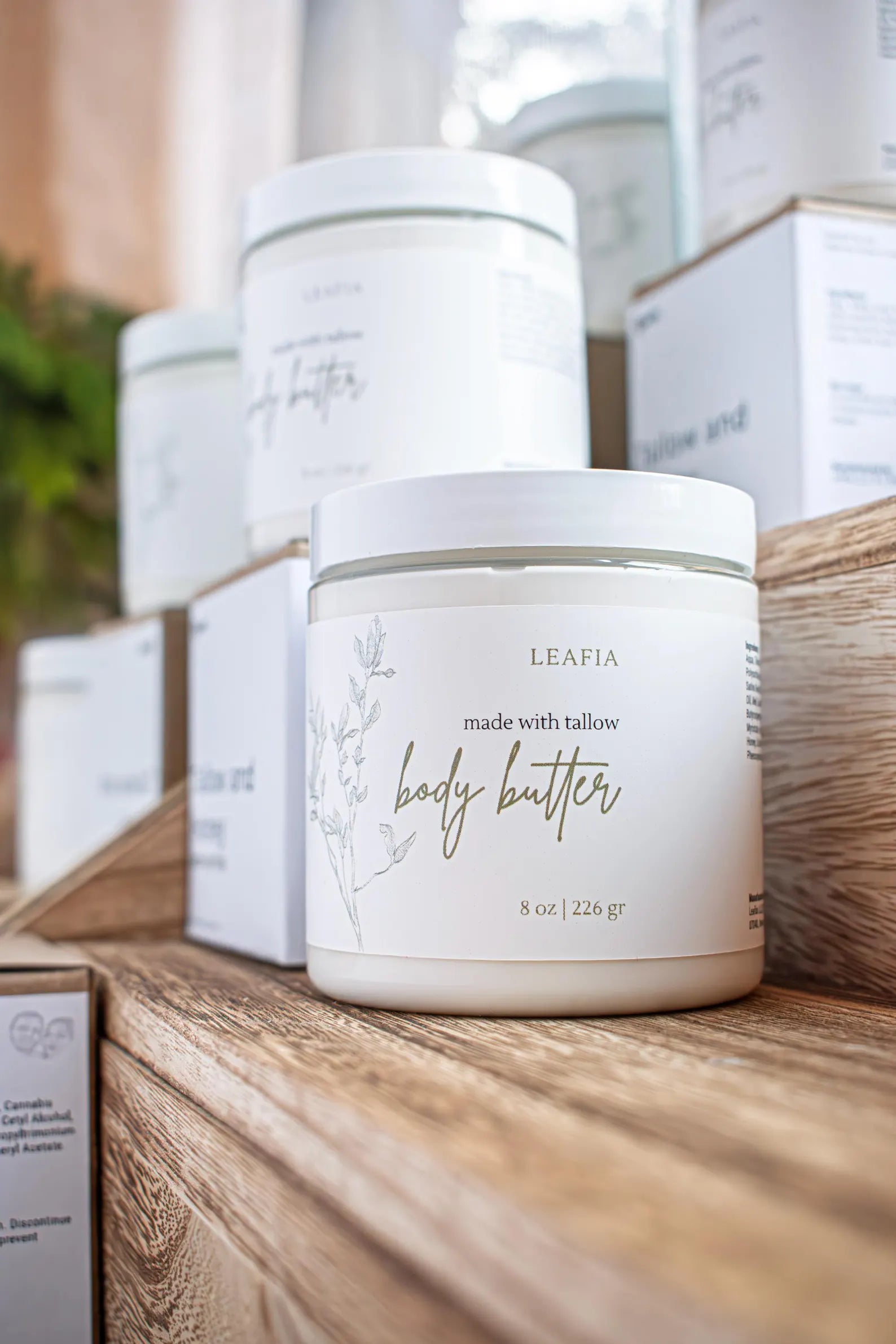 Leafia Skincare body butter container on a wooden surface with blurred background