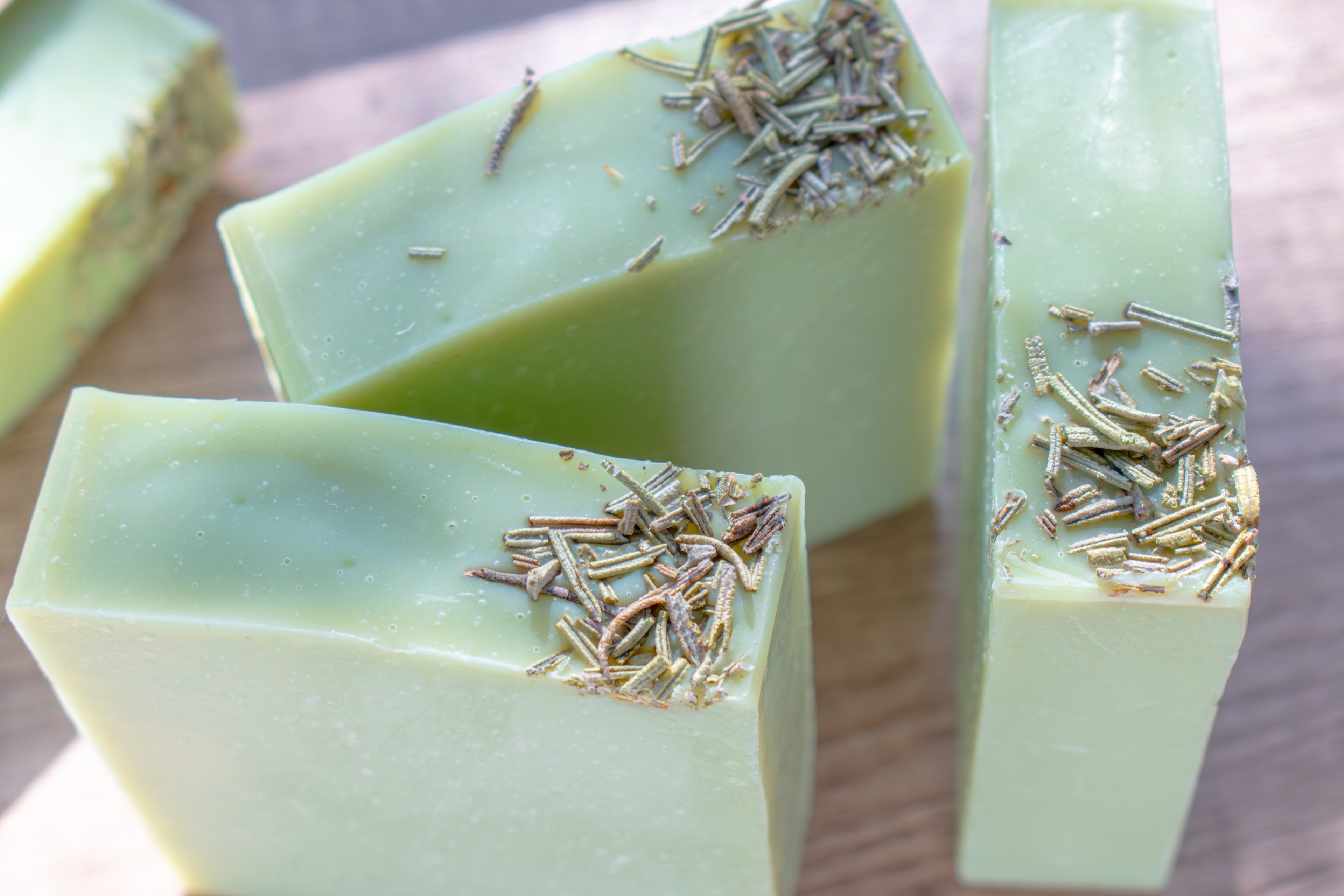 Green soap bars with specks on a wooden surface