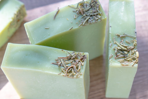 Green soap bars with specks on a wooden surface