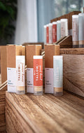 Leafia Skincare tallow lip balm tubes in neutral tones with kraft boxes on rustic wooden shelves in natural light