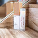 Leafia Skincare lip balm tube standing upright on warm wood surface with minimalist apothecary styling.