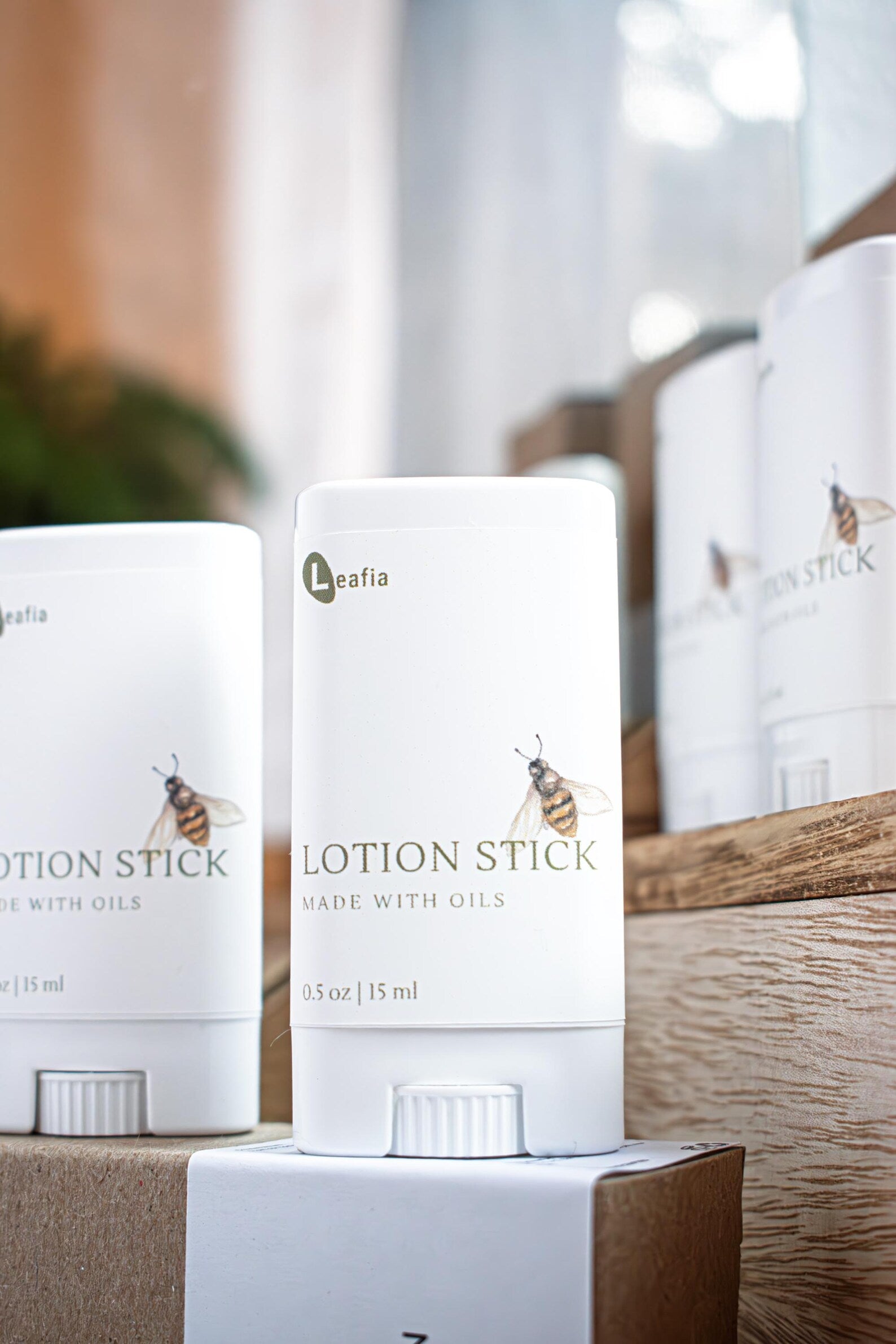 Sweet Almond Oil Lotion Stick by Leafia Skincare in a white twist-up tube, displayed on natural wood blocks with soft lighting and minimal apothecary styling.