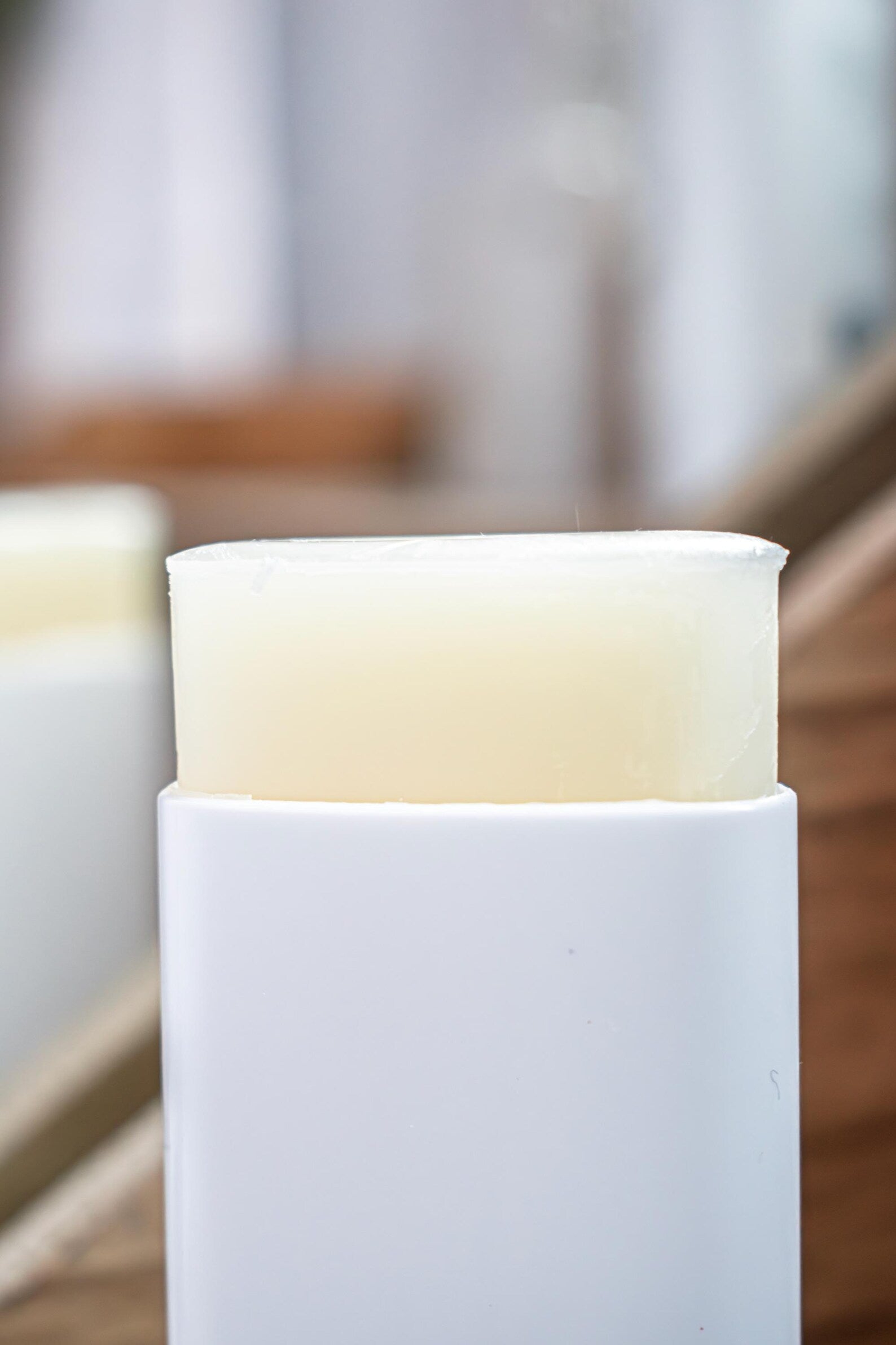 Sweet Almond Oil Lotion Stick by Leafia Skincare uncapped, smooth solid balm in white twist-up container on soft blurred background