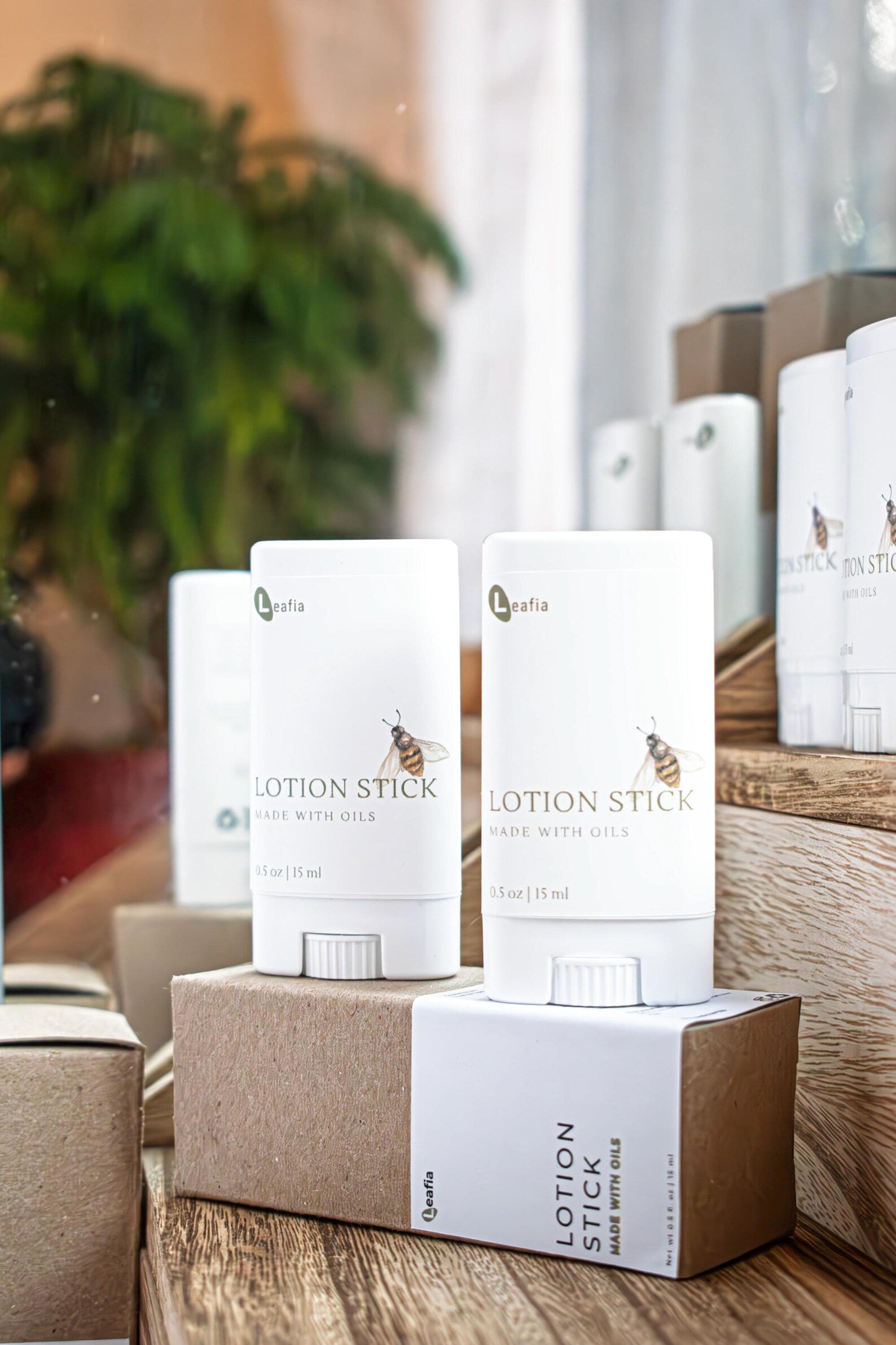 Two Sweet Almond Oil Lotion Sticks by Leafia Skincare on rustic wood near a window, simple packaging in warm natural light