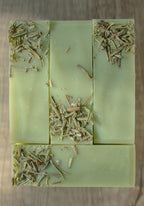 Green soap bar with embedded herbs on a wooden surface