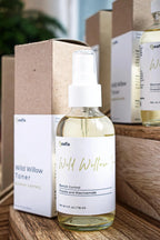 Leafia Skincare Wild Willow Facial Toner in glass spray bottle with clear liquid, minimalist label and kraft box on rustic wooden shelves