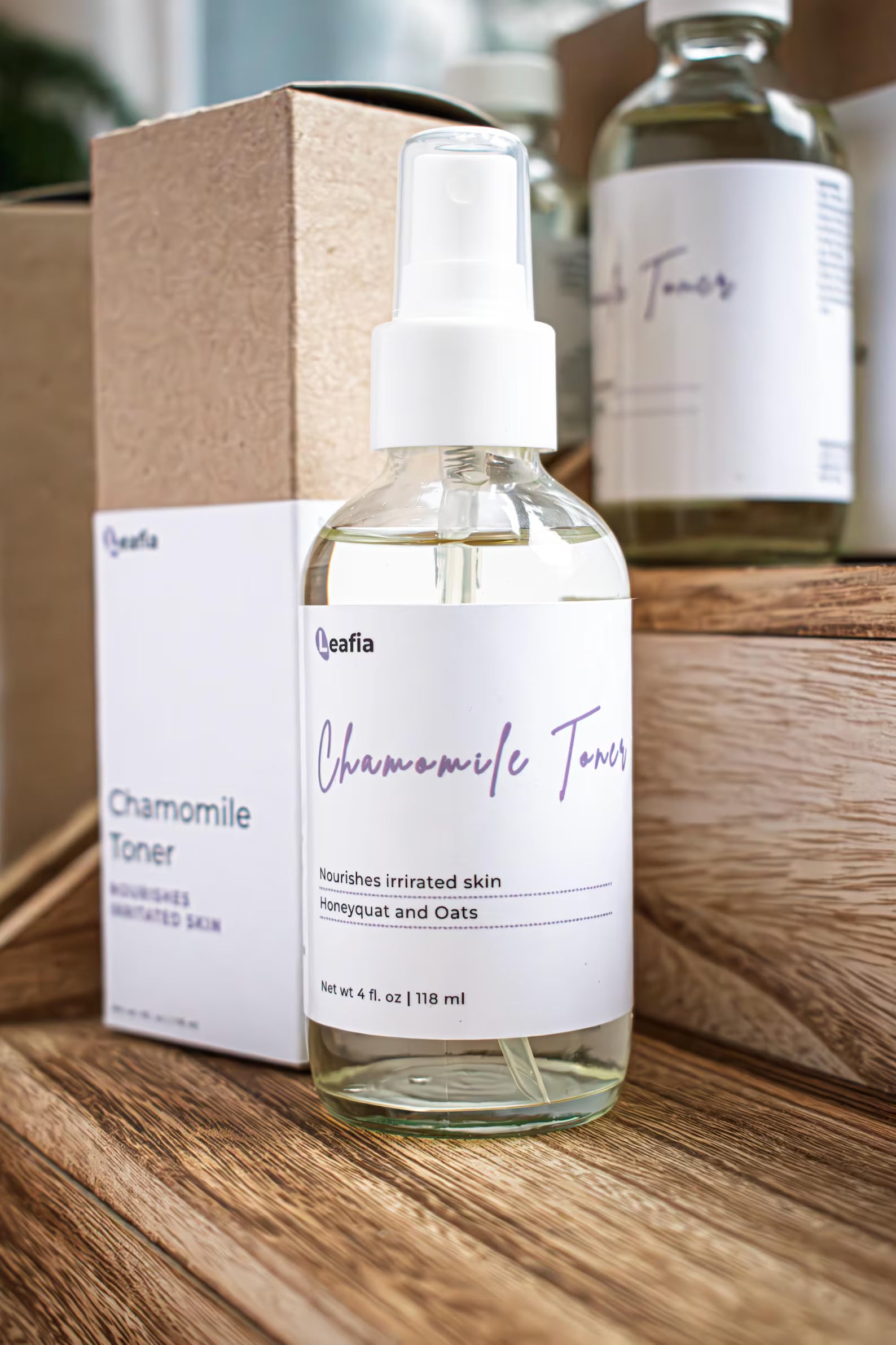 Leafia Skincare Chamomile Toner gentle hydrating facial toner in clear glass spray bottle beside kraft packaging on wooden shelves