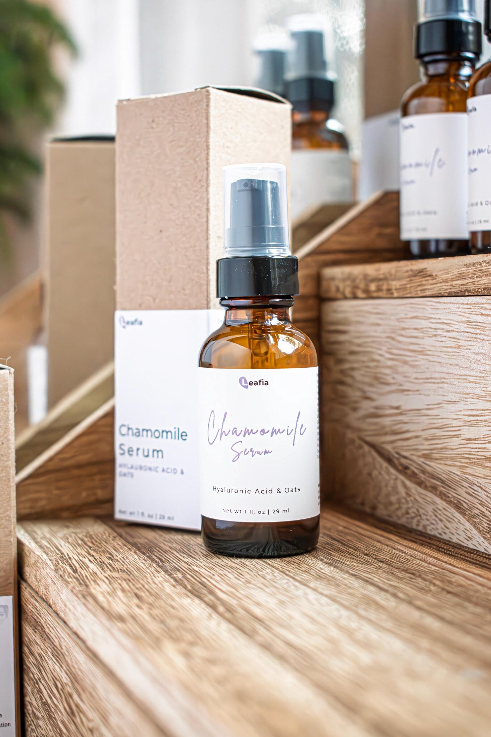 Leafia Skincare chamomile face serum in amber glass pump bottle on wooden surface with minimalist packaging in background
