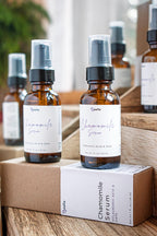 Amber glass bottles of chamomile face serum with pump dispensers displayed on natural wooden blocks in soft daylight. 