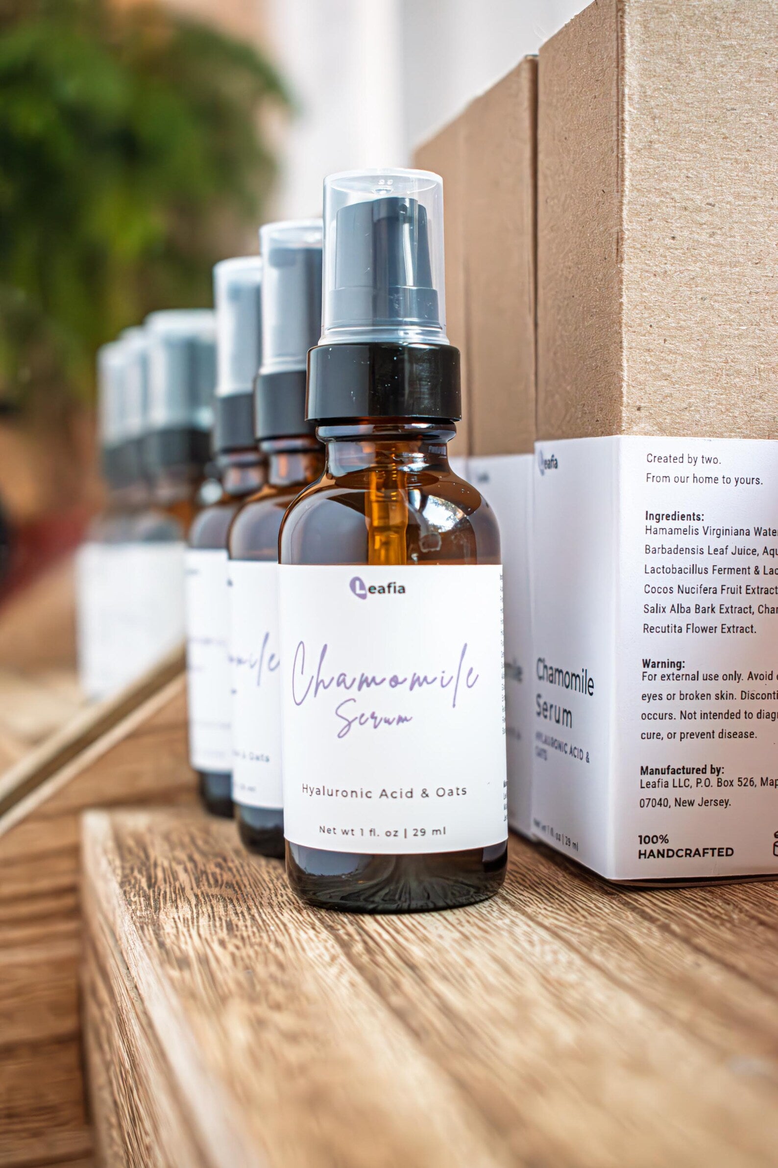 Leafia Skincare chamomile face serum bottles with black pumps on wooden shelves with matching kraft packaging
