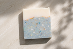 Bar of soap with a blue and white speckled design on a textured surface