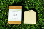 Bar of soap and packaging labeled 'Fresh Aloe' on grass