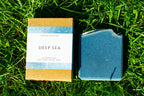 Bar of soap and its packaging labeled 'Deep Sea' on grass