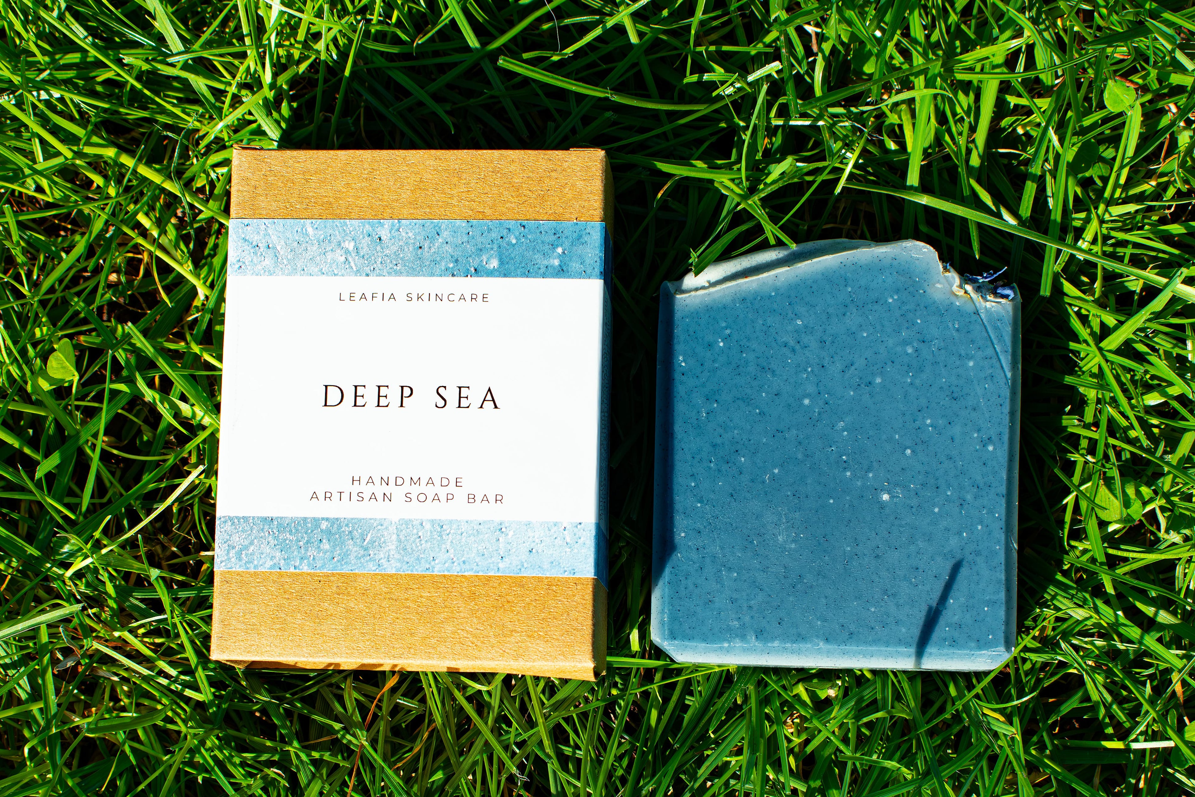 Bar of soap and its packaging labeled 'Deep Sea' on grass