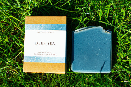 Bar of soap and its packaging labeled 'Deep Sea' on grass
