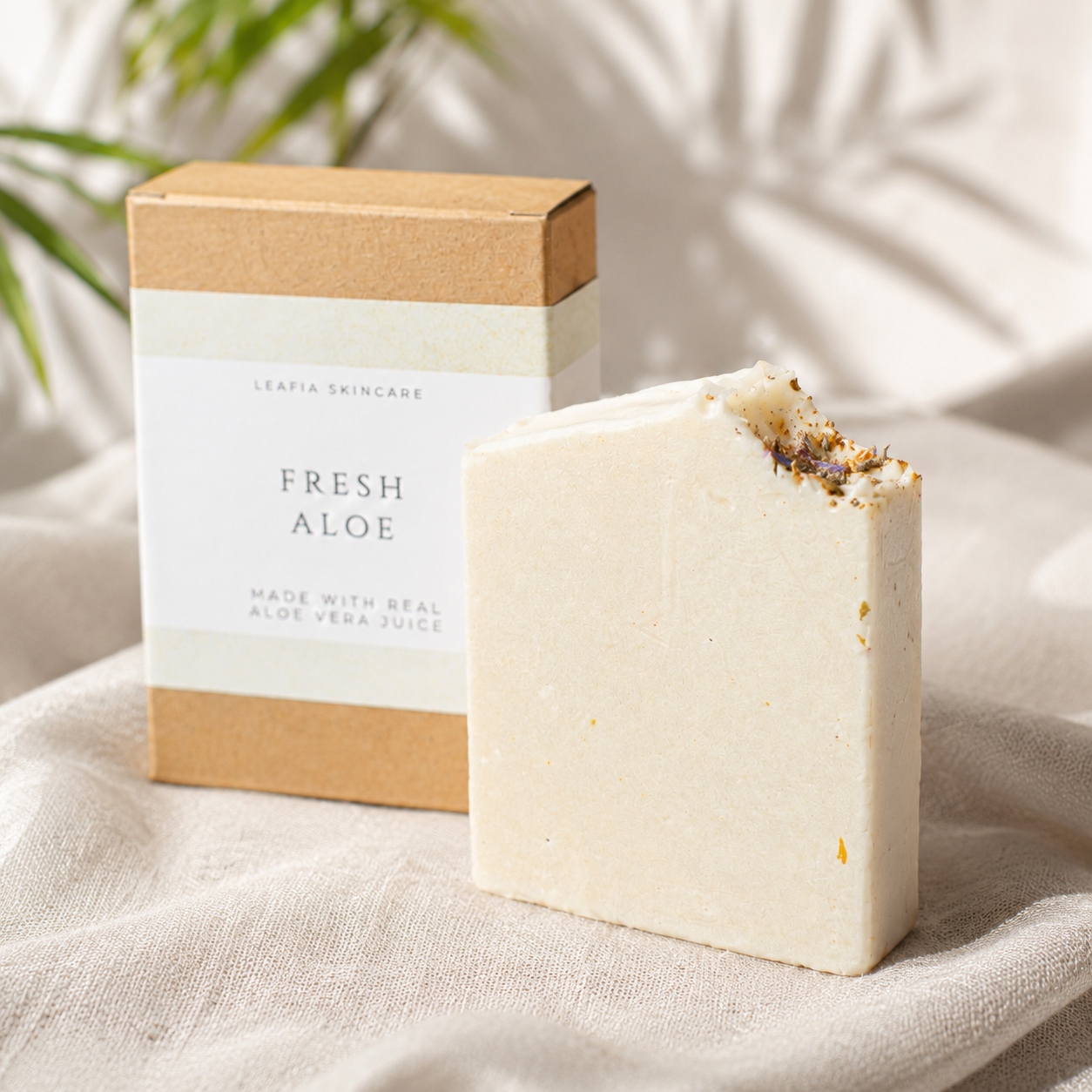 Bar of soap with 'Fresh Aloe' packaging on a textured surface with a plant in the background