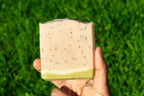 Hand holding a rectangular bar of soap with a green background